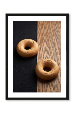 Two Plain Ring Donuts on Minimalist Split Black and Light Wood Surface