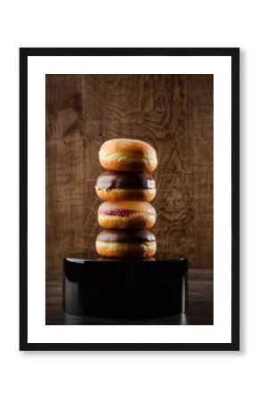 Stack of four Jelly Filled Donuts on Black Pedestal and Dark Wood Background