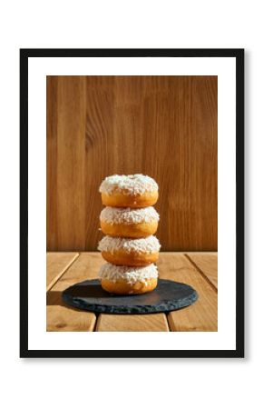 Stack of Four Coconut Glazed Donuts on Wooden Table with Wood Panel Background