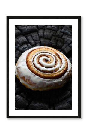 Cinnamon Roll with Icing Glaze on Black Charred Wood Texture