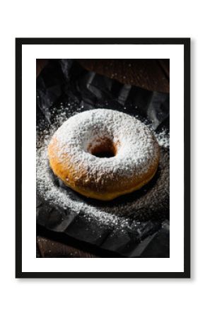 Powdered Sugar Donut on Crumpled Black Paper and Dark Wood