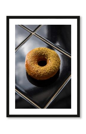 Orange Spiced Donut on Black Glossy Tile Surface with Reflections