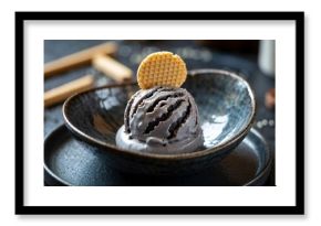 Sleek modern close-up of black sesame ice cream scoop with waffle cookie