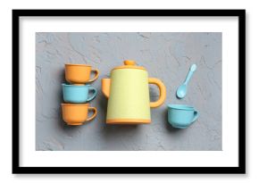Teapot with cups and spoon for baby on grunge grey background