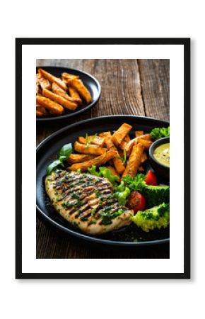 Grilled chicken breast, sweet potato fries with barbecue sauce and boiled broccoli on wooden table 