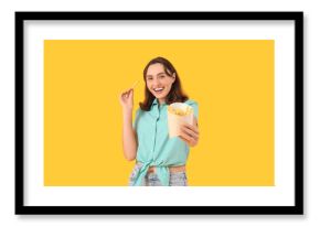Beautiful young woman with french fries on yellow background