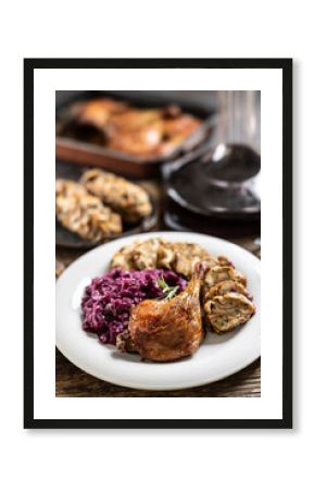 Portion of roast duck leg red cabbage homemade dumplings on plate and red wine on the background