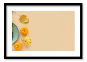 Autumn table setting with pumpkins and dried leaves on beige background