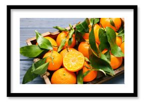 Tray with sweet mandarins and leaves on blue wooden background