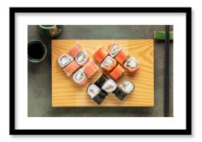 Set of sushi and maki with soy sauce on wooden plate . Top view