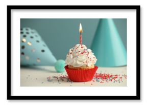 Birthday cupcake with burning candle and party cones on white table