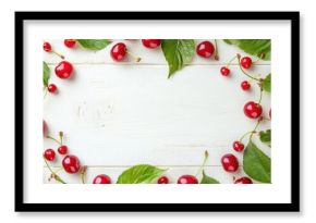 A frame of sweet, juicy cherries and leaves on a white wooden table, viewed from above. Space for text.