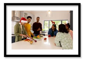 Christmas time, multiracial friends in kitchen preparing holiday meal, wearing festive hats, at home