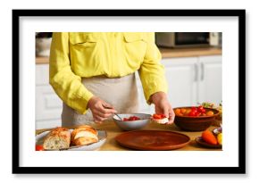 Young woman cooking tasty vegan bruschetta at table in kitchen, closeup