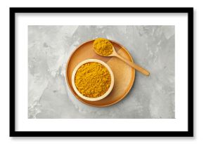 Turmeric powder in bowl and spoon on light grey table, top view