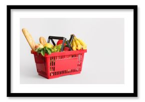 Red shopping basket full of different fresh products and baguette on white background