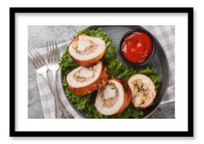 Festive sliced ​​turkey fillet roll with bacon, onions and mushrooms served with ketchup close-up in a plate on the table. Horizontal top view from above