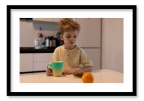 Young boy enjoying breakfast with a cup and fruit in a bright kitchen during morning hours