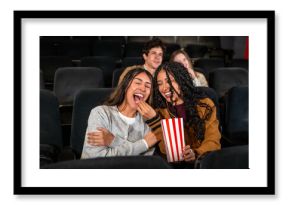 Friends laughing and sharing popcorn at the movie theater