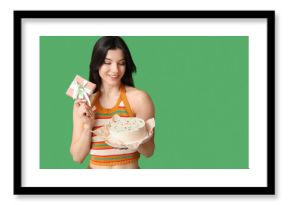 Beautiful young woman with sweet bento cake and gift box on green background. International Women's Day