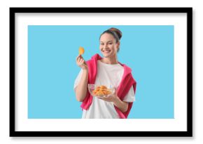 Young woman with bowl of potato chips on blue background