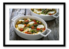 Bread casserole with green asparagus, goat cheese, tomatoes and eggs on wooden table 