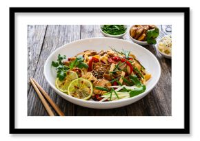 Asian food - chicken nuggets, noodles and stir fried vegetables on wooden table 