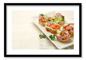 Tasty canapes with salmon served on white wooden table, closeup. Space for text