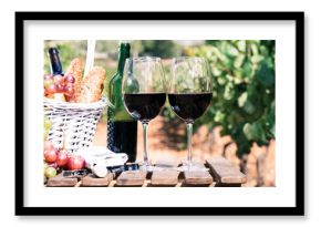 Glass of red wine ripe grapes and picnic basket in vineyard