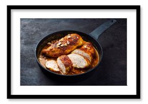 Roasted spicy butter chicken breast fillet in red curry gravy sauce with coconut, lime, and cashew nuts served as close-up in a design frying pan