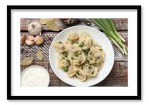 Delicious pelmeni with green onion served on wooden table, flat lay