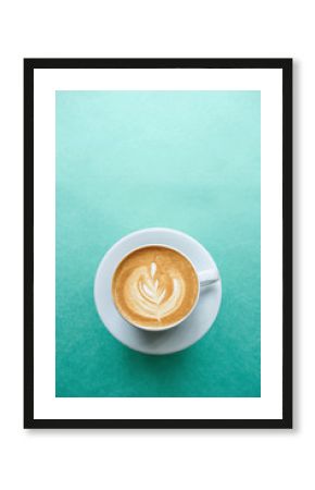 Close up of a cup of fresh cappuccino coffee on a mint background in minimal style.