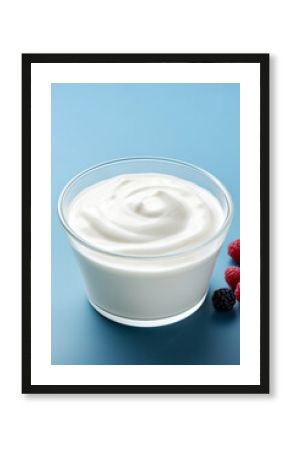 Plain yogurt or Greek yogurt in a bowl served with fresh berries on light blue background