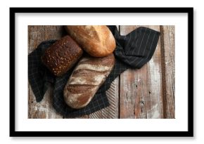 Different types of fresh bread on wooden table, flat lay. Space for text
