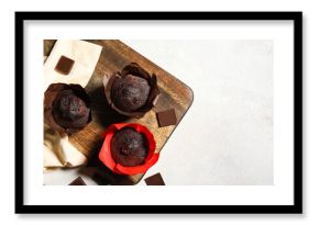 Wooden board with tasty chocolate muffins on white background
