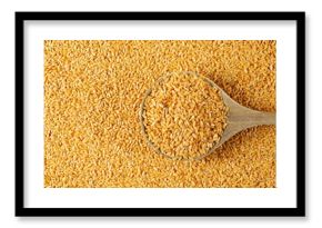 Organic golden flax seeds, linseed grains in wooden spoon background and texture