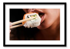 Sushi closeup in sexy woman mouth. Sexy woman eating sushi with chopsticks. Model eat sashimi. Sensual bite of sushi. Female tasting nigiri. Lunch at Japanese restaurant. Desire for delicious sushi.