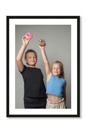 Happy children holding chocolate glazed donut indoor. Happy kids with sweet food portrait