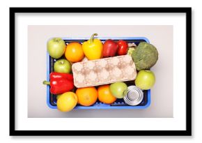Plastic shopping basket full of products on light background, top view