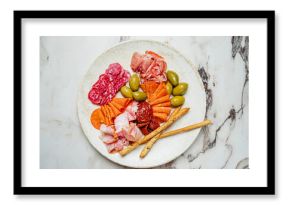 Assorted cured meats, vibrant olives, and crunchy breadsticks create a savory delicacy for sharing