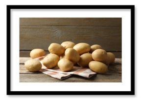 Many fresh potatoes and towel on wooden table
