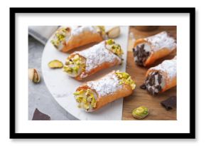 Delicious cannoli with ricotta cheese, pistachios, chocolate and powdered sugar on grey table, closeup