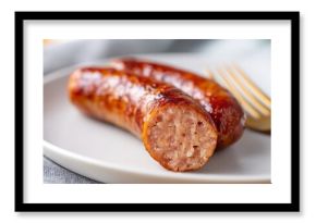Juicy sausage cut open on white plate, close-up food photography with natural daylight