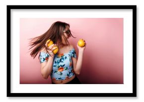 Beautiful dark-haired girl posing with orange fruits and having fun