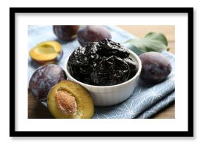 Dried prunes, fresh plums and green leaf on wooden table, closeup