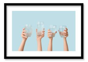 Female hands with glasses of cold water on blue background