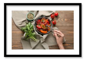 Female hand with fork and bowl of fresh tomato salad on wooden background
