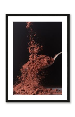Dark cocoa falling onto a spoon. Scene shown against a dark background