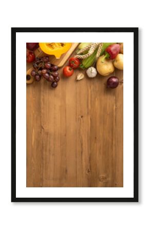 Vertical view of a Thanksgiving harvest featuring fresh fruits, vegetables, and wheat on a wooden surface