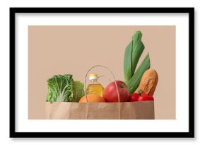 Paper bag with different groceries on beige background, closeup